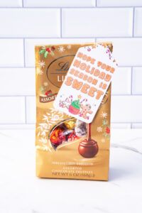 This is one of the free Christmas treat gift tags you can download in this post. It says, Hope Your Holiday Season is Sweet. This fag features a gingerbread man and other sweet Christmas treats. The tag is attached to a bag of Lindor Lindt Truffles.