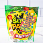 This is one of the free Christmas treat gift tags you can download in this post. It says, Hope Your Holidays are Sweet Not Sour. This Sour Patch Kids-themed tag features hand-drawn Sour Patch kids wearing some snow gear and having a snowball fight. The tag is attached to a bag of Sour Patch Kids ornaments candy.