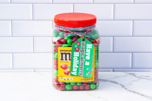 This is one of the free Christmas treat gift tags you can download in this post. It says, Have a Magical & Merry Holiday. It features hand-drawn red and green M&M candies. The tag is attached to a container of Peanut M & Ms.
