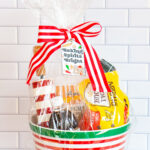  This is one of the free Christmas treat gift tags you can download in this post. It says, Baking Spirits Bright featuring Christmas cookies and baking supplies. It is attached to a gift basket filled with Christmas baking supplies, a Christmas red and white stripped rolling pin, and a red and green spatula.