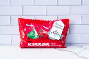 This is one of the free Christmas treat gift tags you can download in this post. It says, Merry Kissmas and featuring Hershey Kisses in their iconic Christmas design in the shape of a bell. The tag is attached to a bag of Hershey kisses.