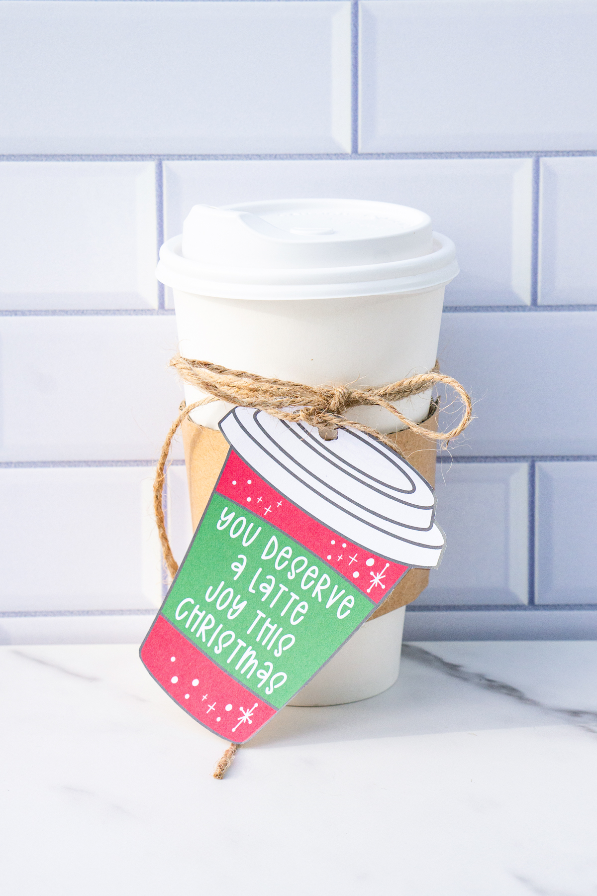 This is one of the free Christmas treat gift tags you can download in this post. It says, You Deserve a Latte Joy this Christmas. It is on a hand drawn coffee cup tag that is red with snowflakes. The tag is attached to a to go cup of coffee.