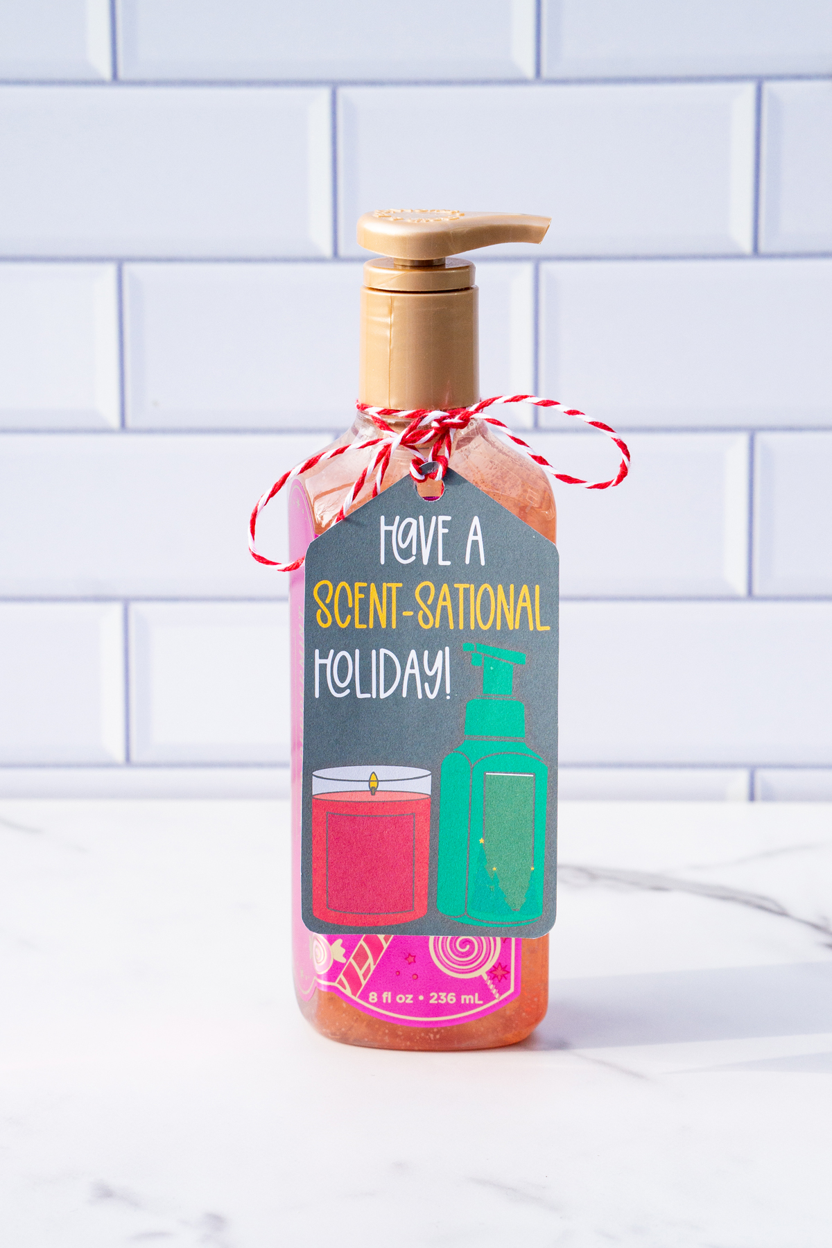 This is one of the free Christmas treat gift tags you can download in this post. It says, Have a Scent-Sational Holiday. It features a candle and a soap pump dispenser. The tag is attached to a Peppermint Twist hand soap container.