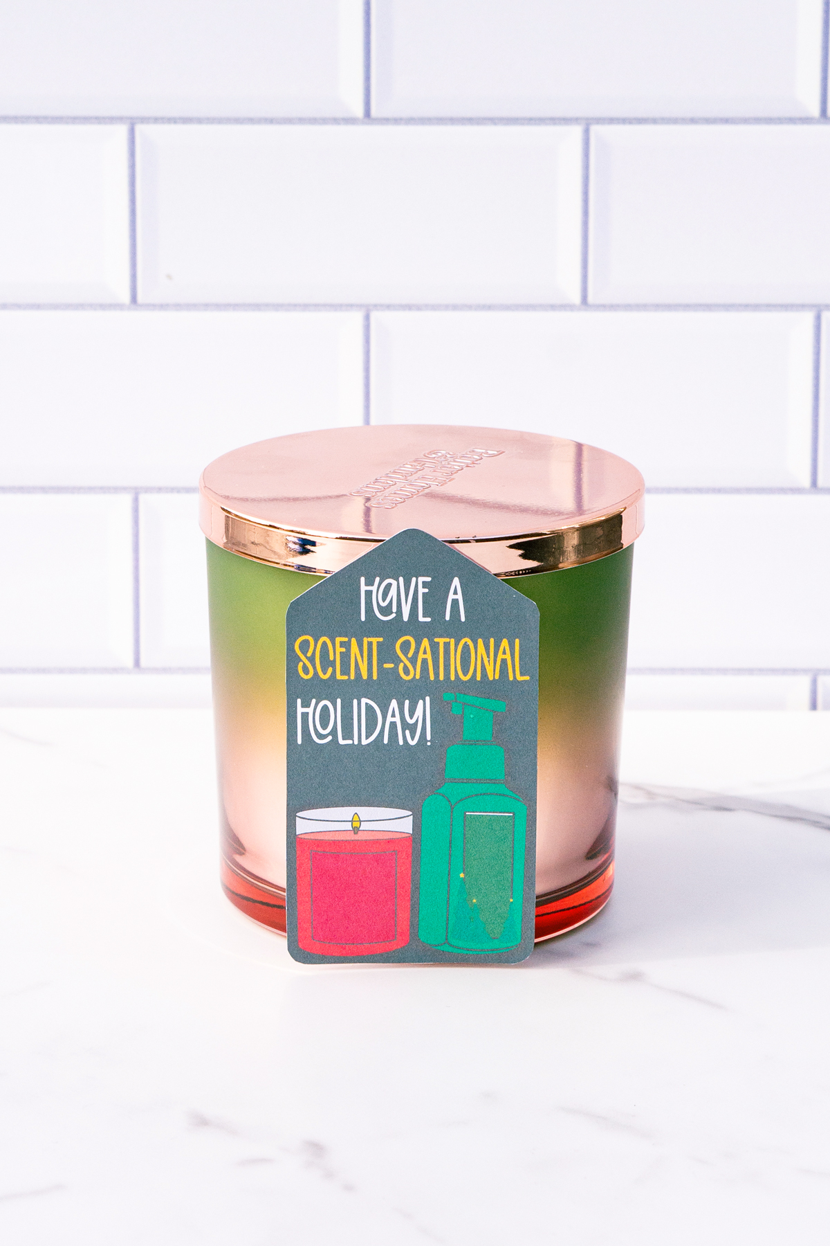This is one of the free Christmas treat gift tags you can download in this post. It says, Have a Scent-Sational Holiday. It features a candle and a soap pump dispenser. The tag is attached to a candle.