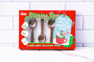 This is one of the free Christmas treat gift tags you can download in this post. It says, You’re Worth Melting For. It features a marshmallow snowman soaking in hot cocoa in a mug with some cookies and treats surrounding the mug. The tag is attached to a box of chocolate spoons.