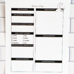 Printed dream log page displayed against a white subway-tile wall, showing sections for dream details, vibe checkboxes, notes, dream interpretation, and mood reflections.