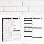 Two printed pages&mdash;dream tracker and dream log&mdash;laid side by side on a white subway-tile background, showing the monthly grid tracker and detailed dream log layout.