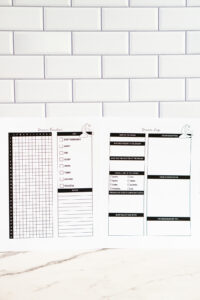 Two printed pages&mdash;dream tracker and dream log&mdash;laid side by side on a white subway-tile background, showing the monthly grid tracker and detailed dream log layout.