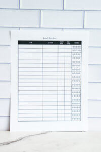 Minimalist reading challenge printable featuring 12 outlined book icons labeled January through December with a notes section at the bottom, displayed against a white tile background.