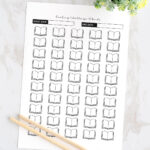 Printed 50 Books Reading Challenge tracker page displayed on a marble surface with two wooden pencils and a small potted plant, featuring rows of open book icons and spaces for start and end dates.
