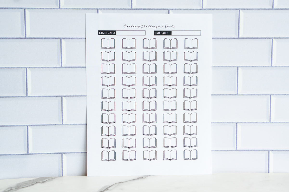 A wide image of a “Reading Challenge: 50 Books” printable sheet with rows of open-book icons and start/end date boxes, positioned against a white tile background.