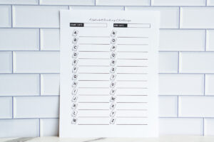 A horizontal photo of an &ldquo;Alphabet Reading Challenge&rdquo; printable page with A&ndash;Z book icons and lined spaces to list book titles, displayed in front of white subway tiles.