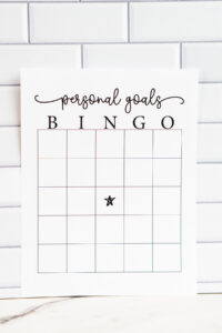 A &ldquo;Personal Goals Bingo&rdquo; printable sheet displayed upright against a white subway tile background, featuring a blank bingo grid with a star icon in the center square.