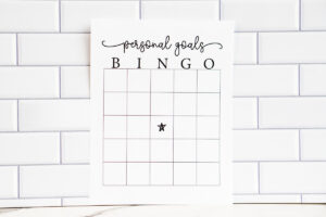 A &ldquo;Personal Goals Bingo&rdquo; printable sheet displayed against a white subway tile background, featuring a blank bingo grid with a small star icon in the center square.