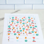 A single advanced Christmas I-Spy worksheet printed in full color, displayed on a marble surface with holiday icons scattered throughout.