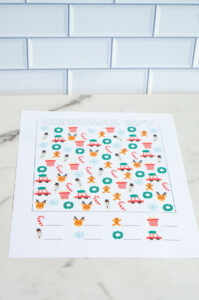 A single advanced Christmas I-Spy worksheet printed in full color, displayed on a marble surface with holiday icons scattered throughout.