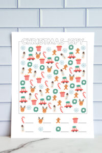 Printed full-color advanced Christmas I-Spy worksheet with a dense arrangement of holiday icons&mdash;reindeer, wreaths, gingerbread men, candy canes, cars with trees, presents, snowflakes, and snowmen. Includes blank spaces for writing totals.