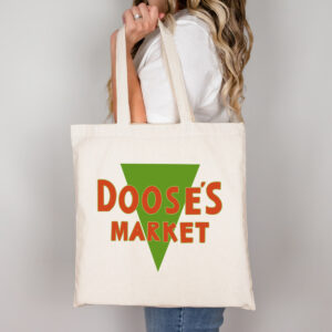 Woman holding a large cream tote bag printed with the green and orange &ldquo;Doose&rsquo;s Market&rdquo; logo.