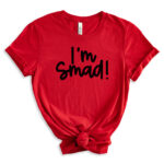 Red T-shirt laid flat with a knotted hem, featuring the phrase ‘I’m Smad!’ in bold black lettering.