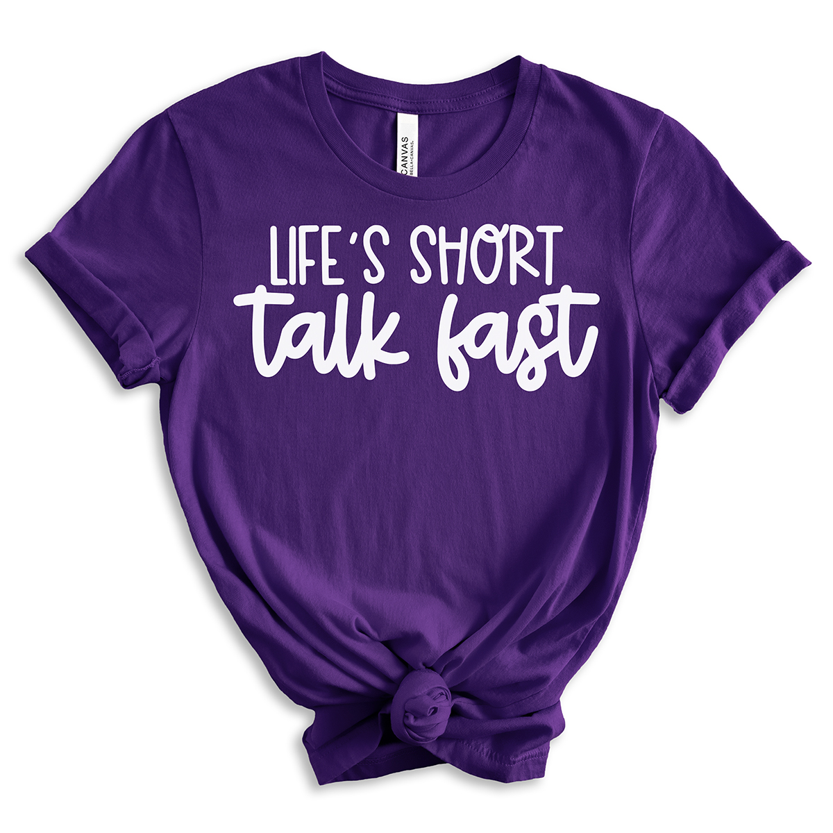 Purple short-sleeve t-shirt with the phrase “Life’s Short, Talk Fast” in bold white lettering, styled with rolled sleeves and a front knot.