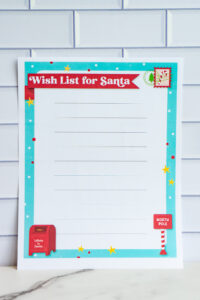 Printable Wish List for Santa sheet with red banner title, lined writing area, and turquoise border decorated with stars, polka dots, a red mailbox, and North Pole sign.