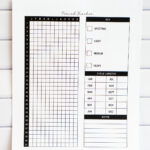 Printed yearly period tracker page displayed against a white subway tile backdrop. The page includes a vertical 31-day grid labeled with months, a symptom key for spotting through heavy flow, a cycle length chart for each month, and a lined notes section.