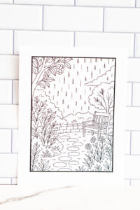 Printable relaxation coloring page featuring a garden scene with a bench, flowers, and rain falling from the sky, displayed against a white tiled background.