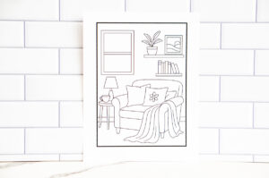 Full view of the cozy reading nook coloring page printed and displayed against a white tile background.
