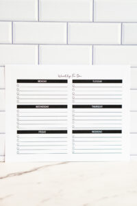 Printable weekly to-do list with sections for each day of the week, displayed against a white subway tile background.