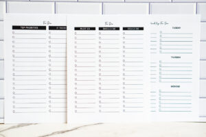Three printable to-do list sheets displayed side by side: a Top Priorities/If There&rsquo;s Time list, a Must/Should/Could Do list, and a weekly to-do list. All shown against a white subway tile background.