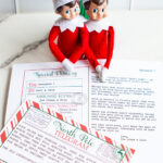 A close-up of two Elf on the Shelf dolls sitting behind a printed North Pole &ldquo;Sorry I&rsquo;m Late&rdquo; letter and telegram with festive red and green accents.