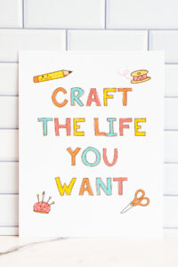 This image shows the free craft themed planner cover you can download in this blog post. It says "Craft the life you want" and is surrounded by hand-drawn looking clip art of a pencil, spool of thread, pin cushion , and scissors.