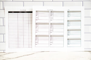A photo of three printable contact list pages standing upright against a white subway-tile background. The left page features a black-topped column layout with rows for names, two phone numbers, and email. The middle and right pages show boxed contact-card layouts in muted colors with spaces for name, phone numbers, email, address, notes, and socials.