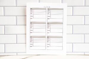 A full-page view of a six-box contact card layout printable page. Each box includes labeled sections for name, phone numbers, email, address, and notes, printed in soft neutral tones and photographed against a white subway-tile background.