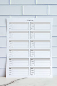 Printable contact list featuring multiple small contact info boxes with space for name, phone numbers, and email, displayed in front of a white tile wall.