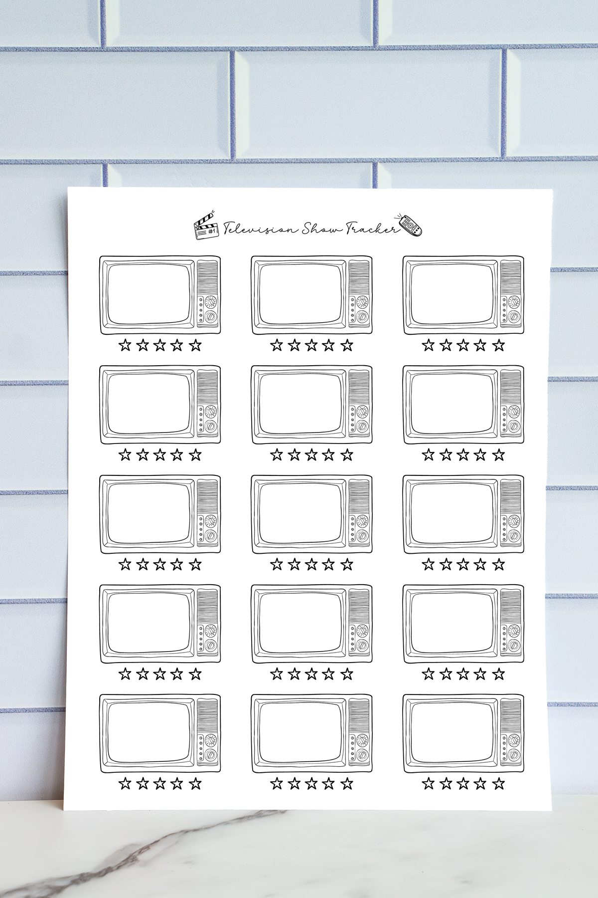A printed TV show tracker page shown against a tile wall. The page includes hand-drawn retro television frames arranged in rows with a line of star ratings beneath each TV illustration.