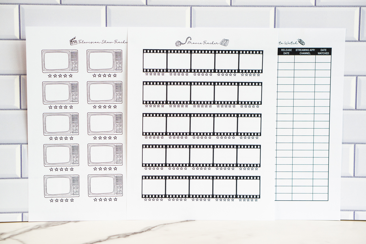 Three printed TV and movie tracker pages displayed side by side against a white subway tile background, including a television show tracker with retro TV icons, a movie tracker with film strip boxes, and a &ldquo;Movies to Watch&rdquo; list with organized columns.