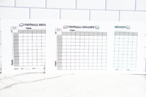 Three football squares printables lined up side-by-side on a white marble surface against a subway-tile wall.
