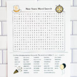 Alt text: A New Year's word search printable displayed against white subway tile, featuring a large word search grid with small festive illustrations like a party hat, disco ball, and balloons, along with a list of themed words to find.
