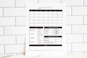 Printed monthly period tracker page displayed against a white subway tile background. The page features a blank monthly calendar grid, a symptom key including spotting, cramps, mood swings, and more, a section to rate the month&rsquo;s period (on time, early, late, normal, worse, better), a period stats table, and a large notes area at the bottom.