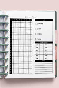 A close-up of a printable annual period tracker page inside a ring-bound planner. The left side shows a grid labeled with months and numbered days, and the right side has symptom boxes, cycle length tracking, and a notes section. Planner tabs and metal rings are visible.