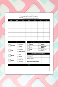 A monthly period tracker printable displayed on a pink background covered with overlapping menstrual pads. The page includes a calendar grid, symptom checklist, a section for rating the month&rsquo;s period, cycle stats, and a notes box.