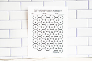 A printed honeycomb-style &ldquo;My Weightloss Journey&rdquo; tracker displayed against a subway tile wall in landscape orientation. The chart includes numbered hexagons arranged in rows with goal, start date, and end date fields at the top.
