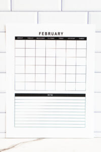 Close-up vertical view of the undated February calendar with a simple grid and a bold black Notes header above the lined notes area, shown against a white tile background.