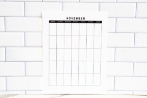 Horizontal undated November calendar page displayed against a white subway tile background with a marble surface in front.