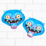 Two finished Valentine cards shaped like a blue cartoon blue Derpy from KPop Demon Hunters. They are placed on a white tile surface. Each demon has bright blue skin, pointed ears, glowing yellow-to-orange eyes, and a wide open mouth with sharp white teeth. A small Valentine card sticks out of each demon&rsquo;s mouth like a tongue, with one reading &ldquo;Happy Valentine&rsquo;s Day&rdquo; and the other reading &ldquo;Hello Friend."