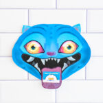 A single KPop Demon Hunters Inspired Valentine card shaped like a blue cartoon blue Derpy from KPop Demon Hunters. It is placed on a white tile surface.The Derpy looks like a blue tiger - has bright blue skin, pointed ears, glowing yellow-to-orange eyes, and a wide open mouth with sharp white teeth. A small Valentine card sticks out of its mouth like a tongue, with one reading &ldquo;Hello Friend."