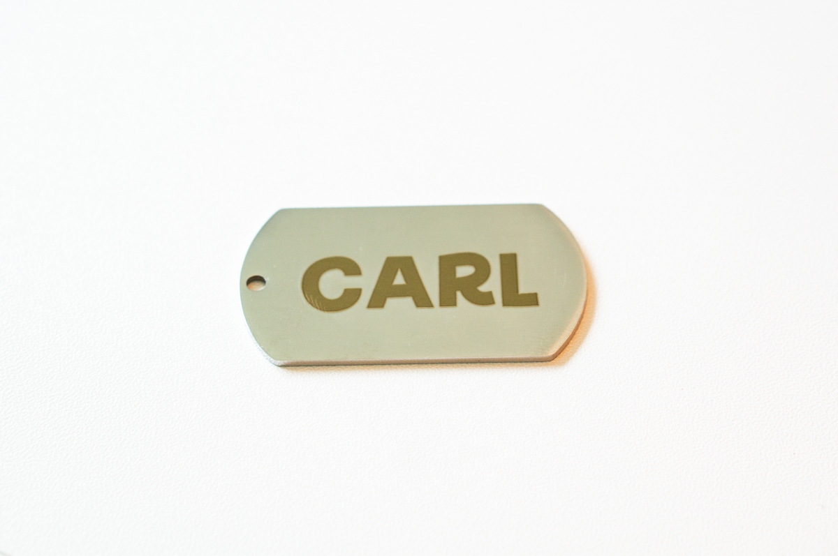 Brushed metal dog tag engraved with the name "Carl" using the xTool F2 laser engraver.