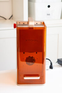 Front view of the compact xTool F2 desktop laser engraver with the orange protective enclosure closed.