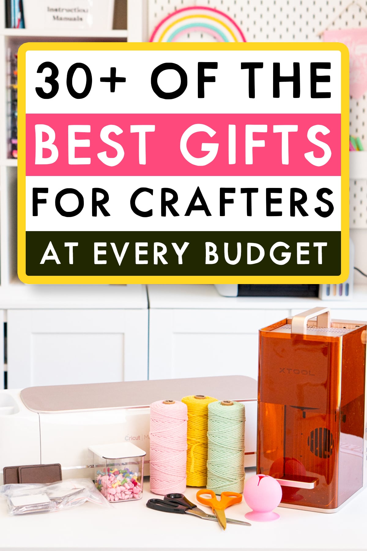 Tall Pinterest graphic for a crafter gift guide featuring an organized craft room and a table filled with crafting supplies, including a Cricut cutting machine, orange-covered xTool laser machine, pink, yellow, and mint green twine, scissors, craft blanks, a storage container, and a pink vinyl scrap collector. A large white, pink, and dark green text box with a yellow border reads